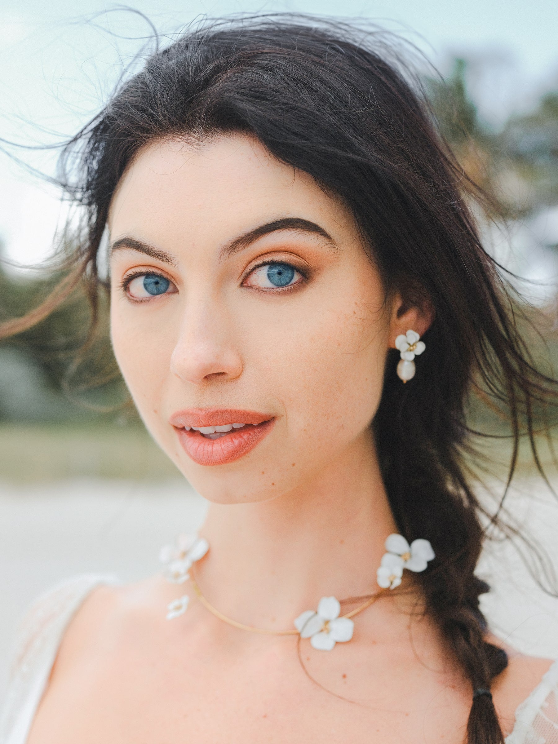 Elegante parure da sposa con collana e orecchini decorati con fiori bianchi, per un look sofisticato e armonioso.