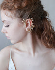 Accessorio orecchio: ear cuff dorato con design floreale delicato.