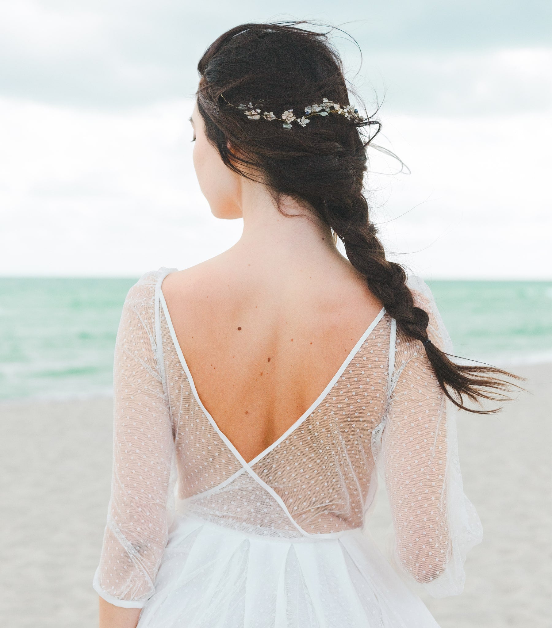 Acconciatura da sposa romantica con coroncina floreale e perle blu.