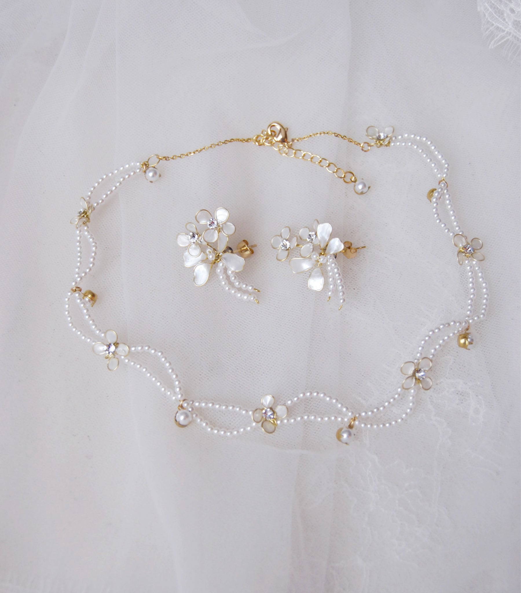 Set di gioielli da sposa con collana e orecchini coordinati, arricchiti da perline e fiorellini delicati, per un look elegante e raffinato.