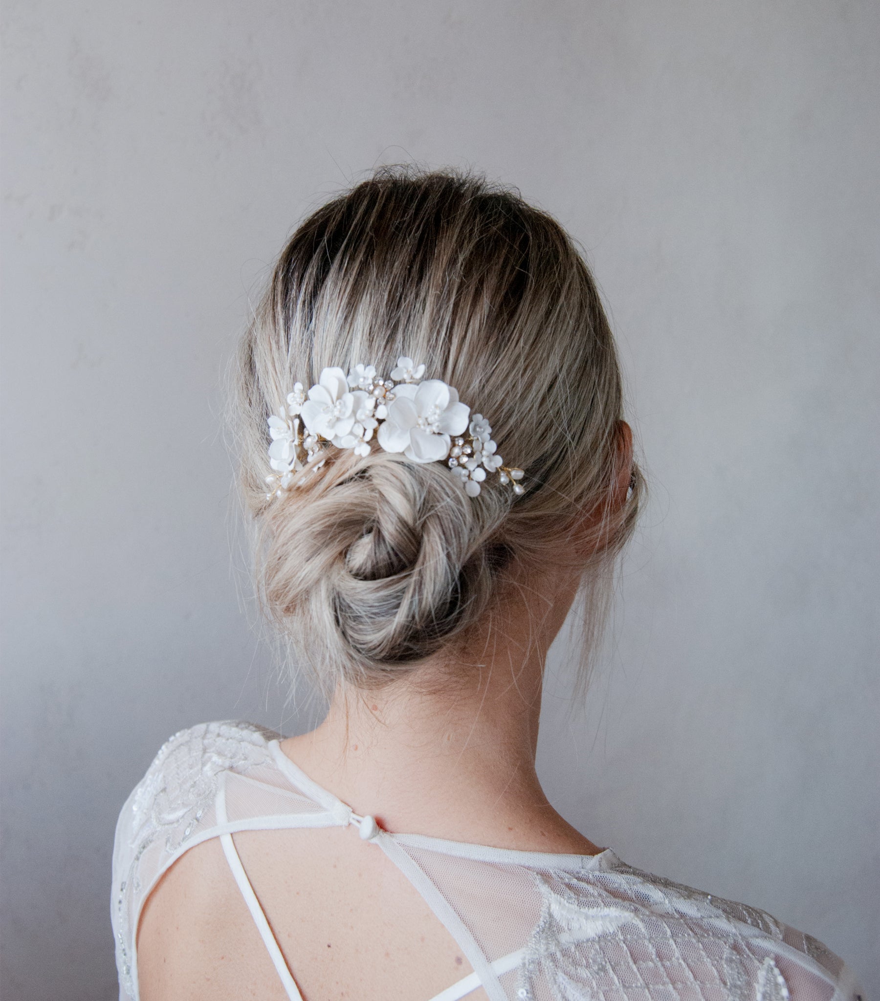 Accessorio per capelli bianco con peonie e fiorellini, aggiunge eleganza al look nuziale.