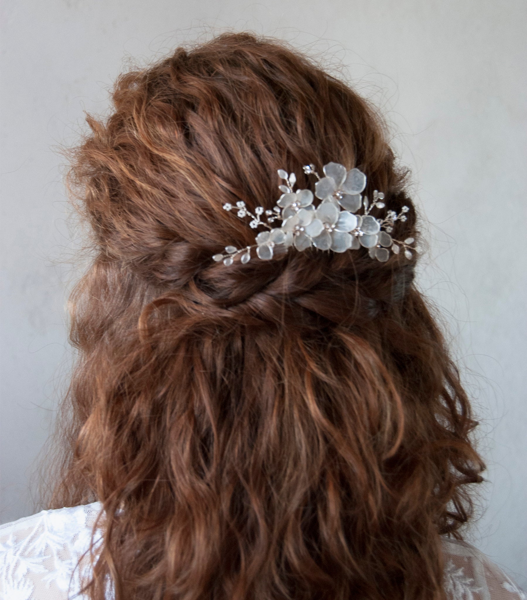 Accessori per capelli da sposa con fiori satinati, ideali per un’acconciatura raffinata.