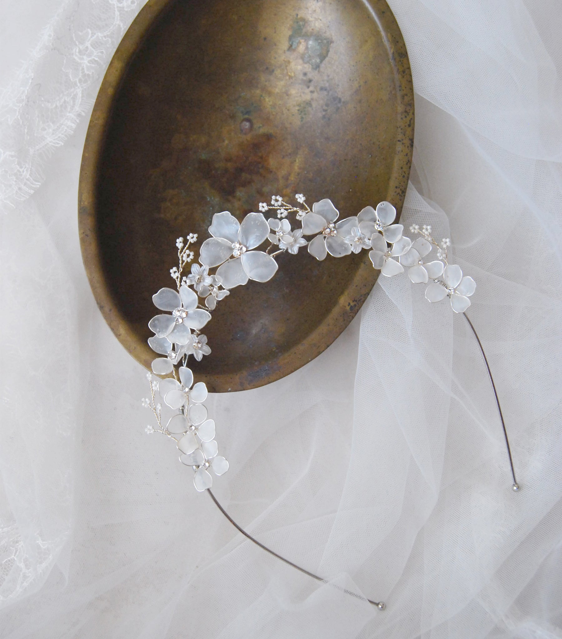 Tiara elegante con fiori bianchi satinati, perfetta per completare un'acconciatura da sposa romantica.